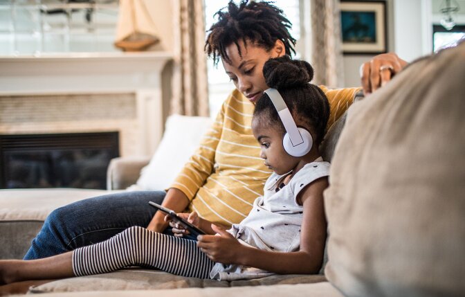 Mother and daughter on couch using tablet