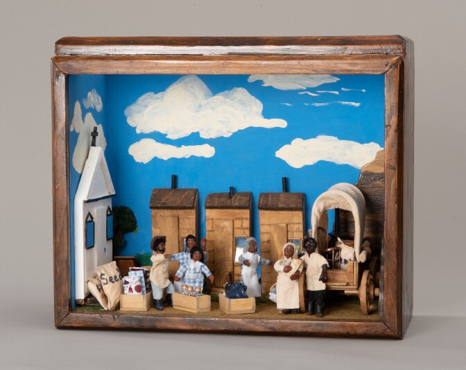 A shadowbox miniature diorama with wooden frames depicts a scene where Exodusters arrive in a Western town. The Exodusters, all African American, are seen gathered by a carriage with their items being unloaded.