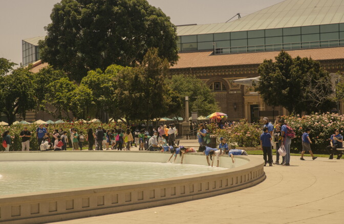 view of a fountain surrounded by children in a middle of a large garden