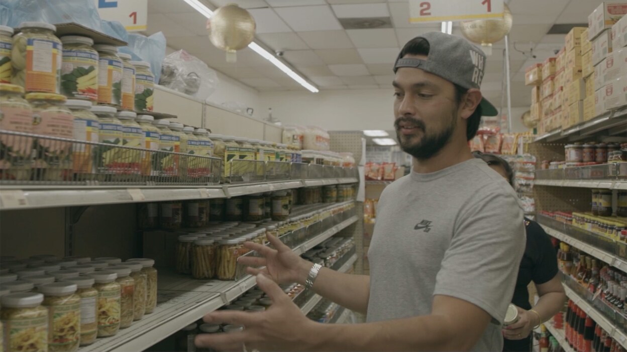 Louis Tikaram of EP/LP showing Bangkok Market products | Still from "The Migrant Kitchen" Louis and Jazz
